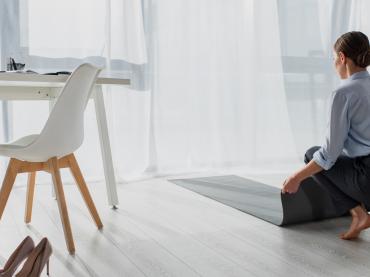 Woman In Business Outfit Kneeling Down On Yoga Matt In Office Setting