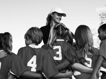 Woman Coach In Baseball Hat Surrounded By Kids In Team Uniforms